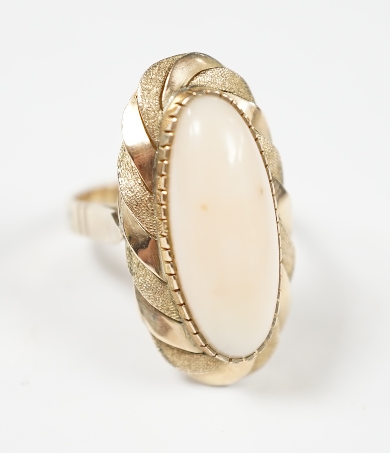 A yellow metal and single stone cabochon white coral set oval ring, size Q, gross weight 7.6 grams.